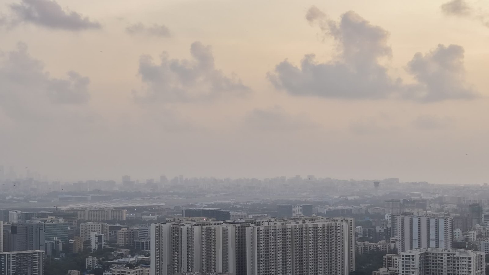 Drone photo of Mumbai's towers fading into a grey haze under a pale evening sky
